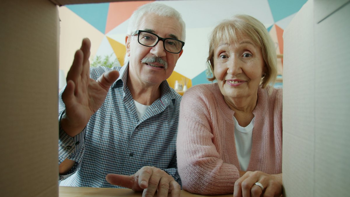 An older couple unpacking a moving box