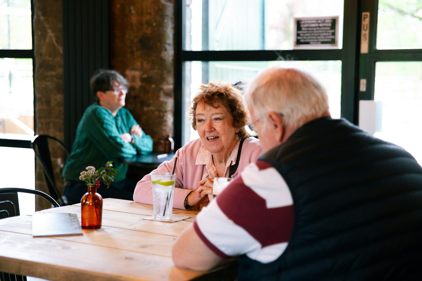 Friends in their seventies chatting over coffee in a cafe