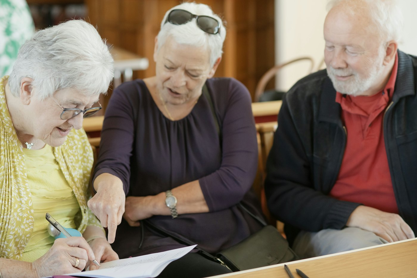 Three older people reading a letter together